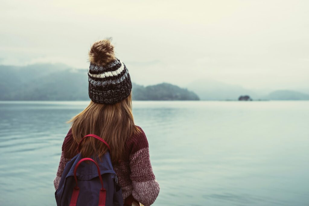 Lonely woman standing absent minded and looking at the river