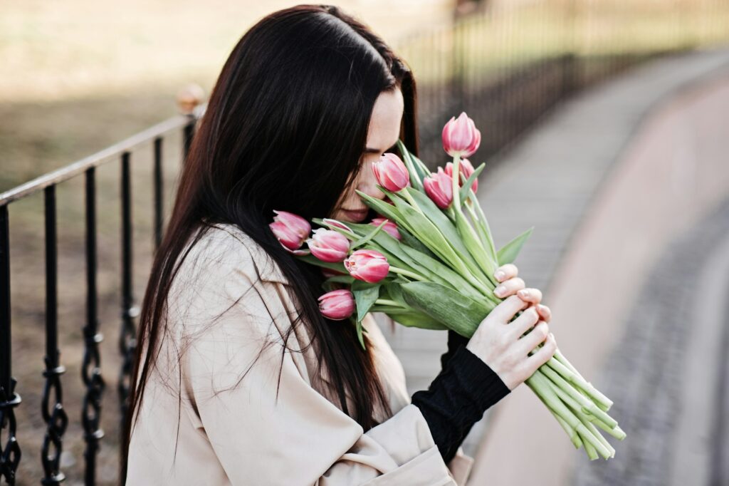 Spring, self love, self care. Candid portrait of happy woman with tulips bouquet outdoors