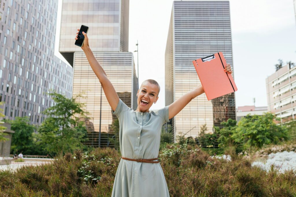 Triumphant Caucasian Businesswoman with Short Hair and Mobile Phone